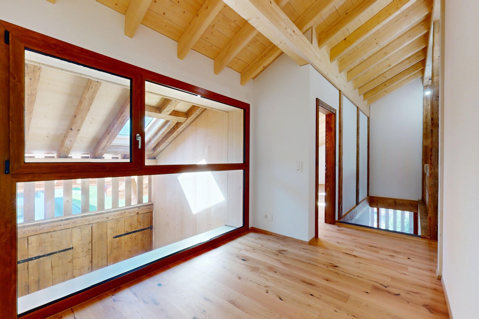 pièce vide avec plafond voûté, plafond à poutres, lumière naturelle, et sol en finition bois