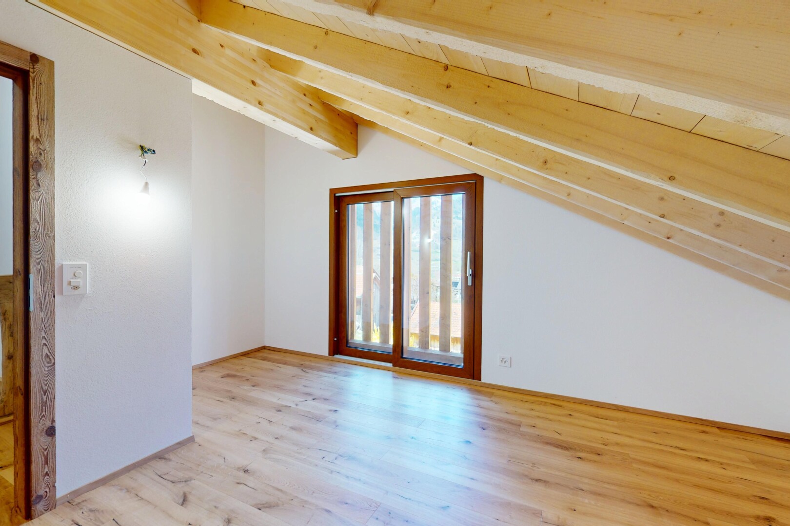 pièce vide avec cloison sèche, lumière naturelle, plafond voûté, et sol en finition bois