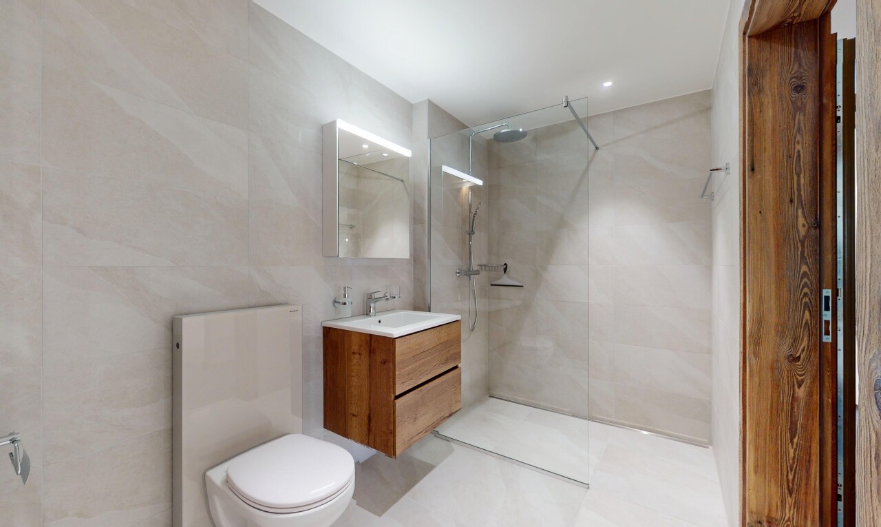 salle de bains avec évier, douche, lavabo (ou coiffeuse selon le contexte), mur en carrelage, et miroir