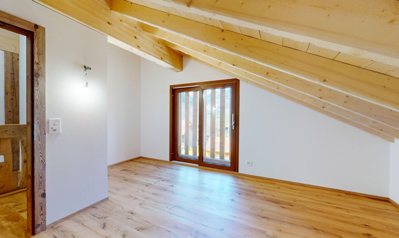 pièce vide avec cloison sèche, lumière naturelle, plafond voûté, et sol en finition bois