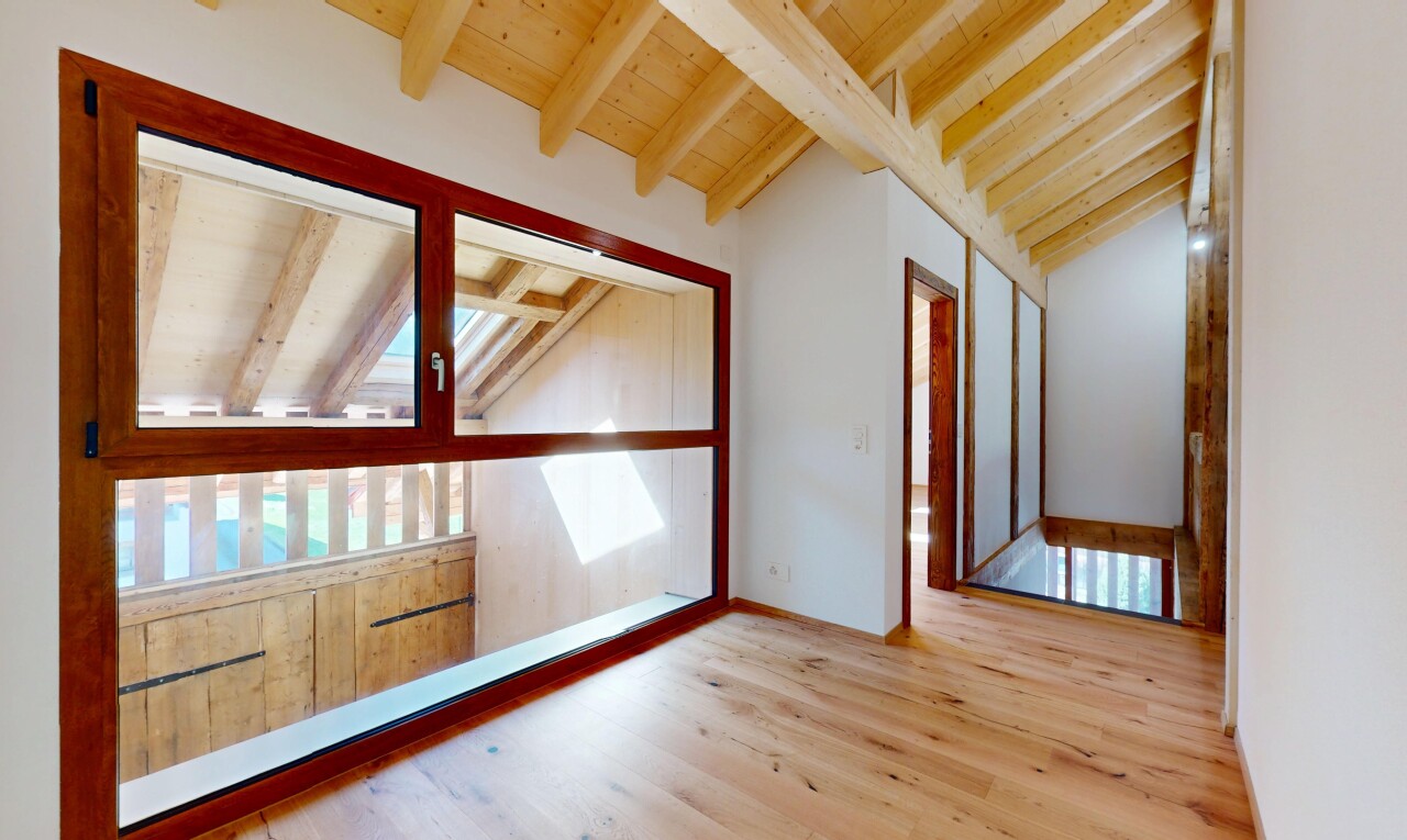pièce vide avec plafond voûté, plafond à poutres, lumière naturelle, et sol en finition bois