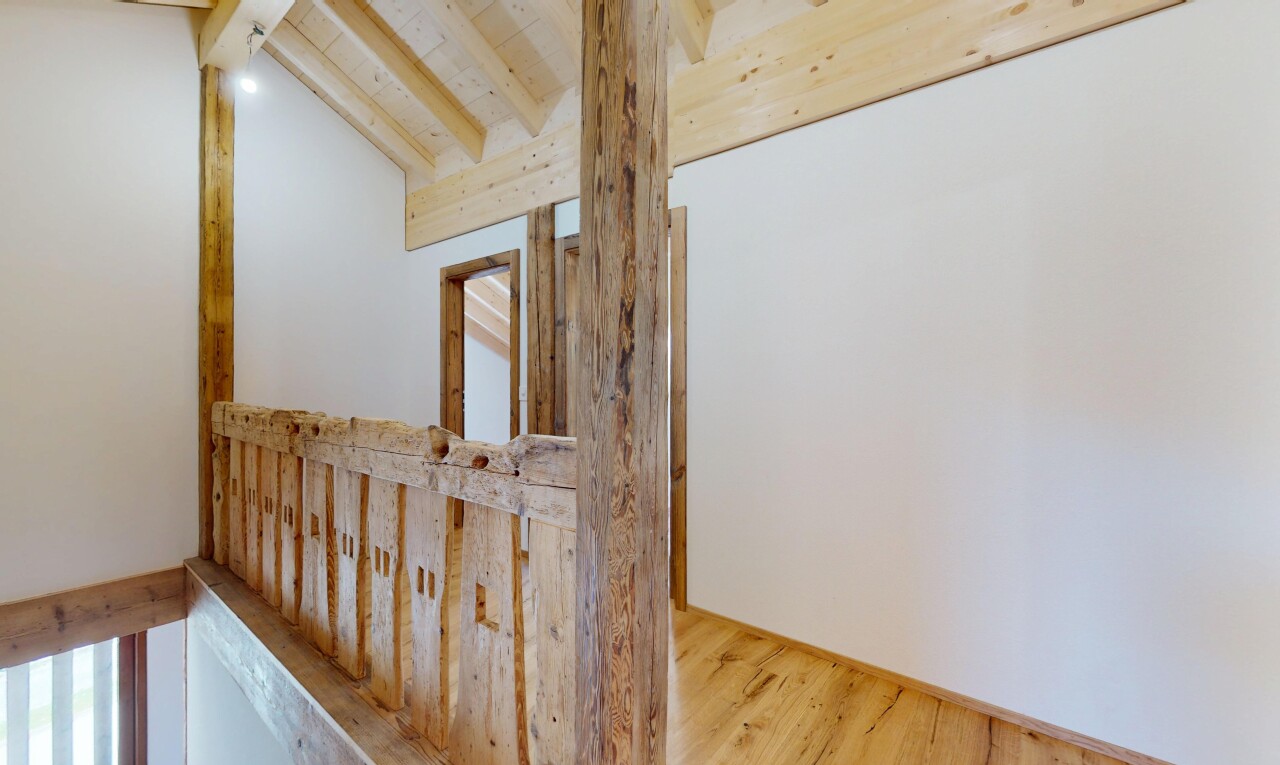 couloir avec cloison sèche, plafond voûté, plafond à poutres, et sol en finition bois