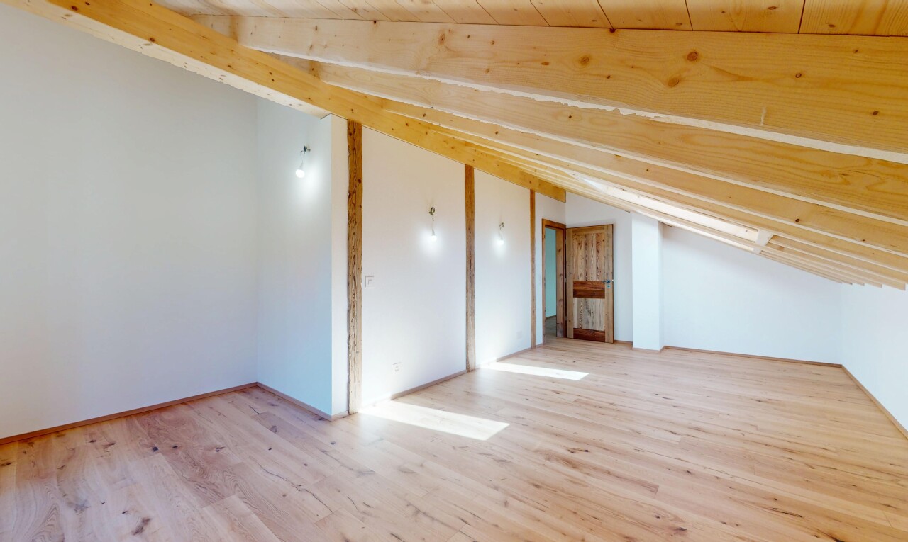 pièce vide avec cloison sèche, plafond voûté, et sol en finition bois