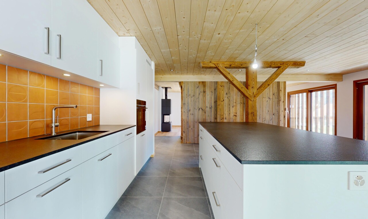 cuisine avec dosseret, évier, plafond en bois, et plans de travail