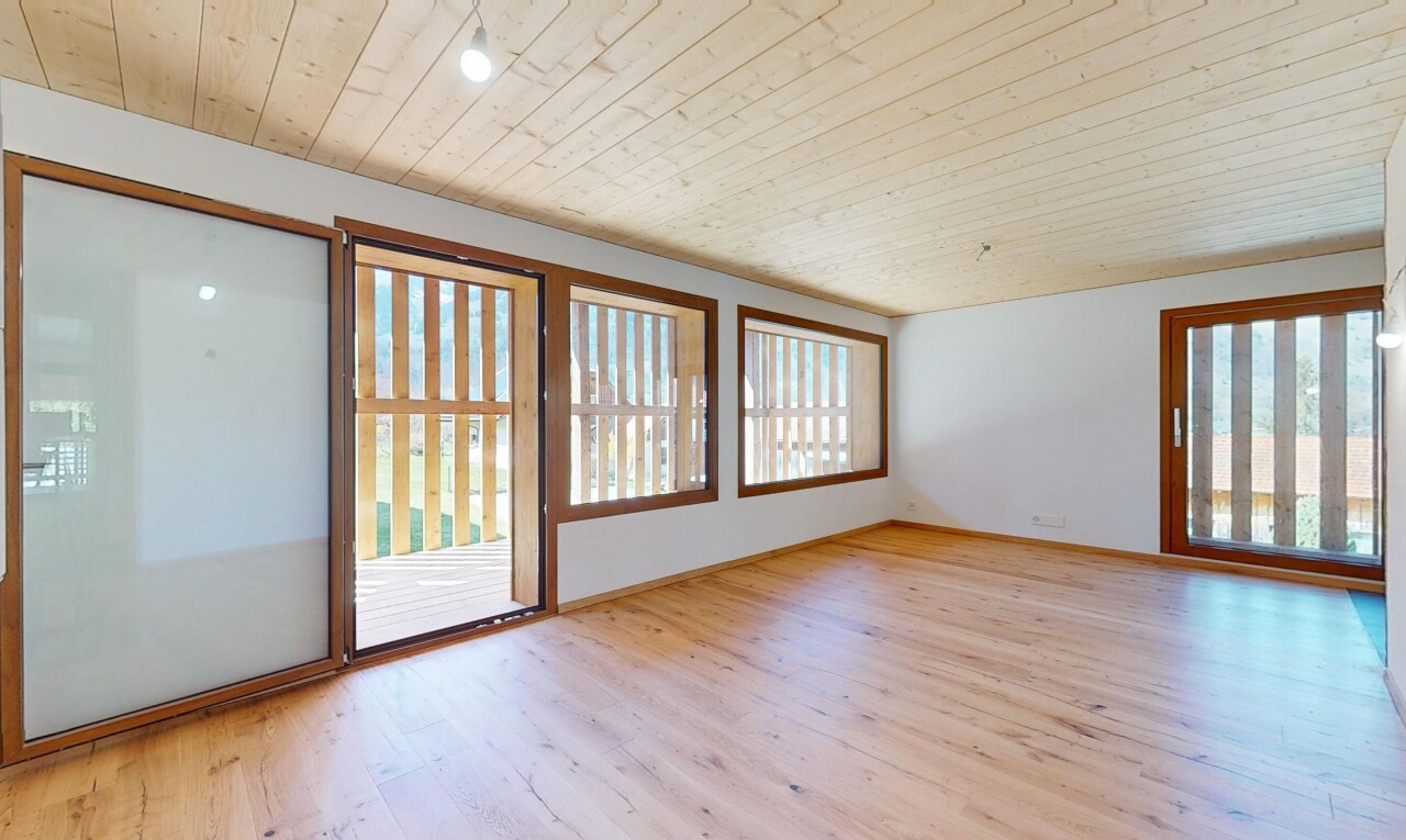 pièce vide avec lumière naturelle, plafond en bois, cloison sèche, et sol en finition bois