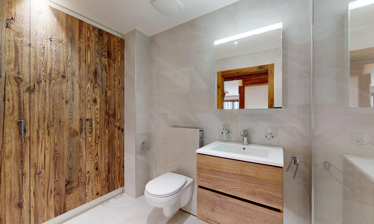 salle de bains avec évier, lavabo (ou coiffeuse selon le contexte), toilette, mur en carrelage, et miroir
