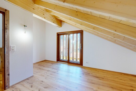 pièce vide avec cloison sèche, lumière naturelle, plafond voûté, et sol en finition bois