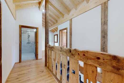 couloir avec cloison sèche, plafond voûté, sol en finition bois, plafond à poutres, et plafond haut