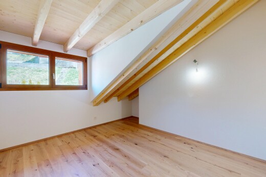 pièce vide avec cloison sèche, lumière naturelle, sol en finition bois, plafond à poutres, et plafond en bois