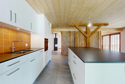 cuisine avec dosseret, évier, plafond en bois, et plans de travail