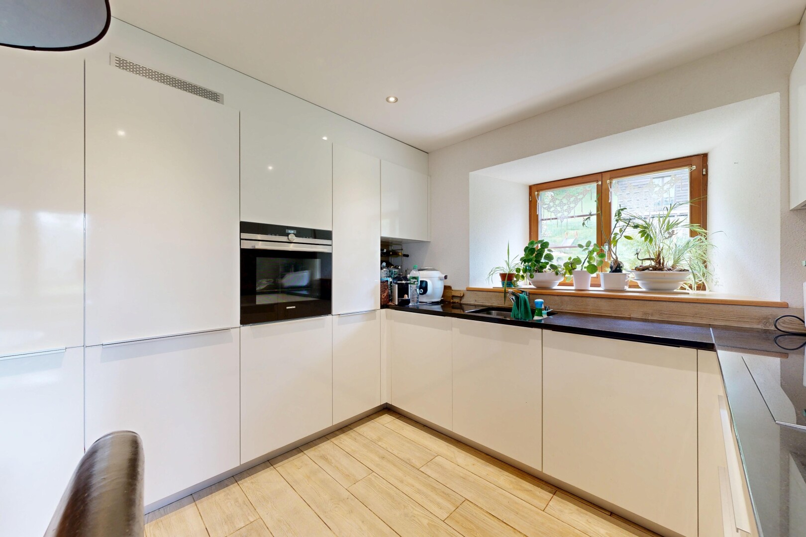 cuisine avec four, plans de travail, dark countertops, light floor, et sol en finition bois