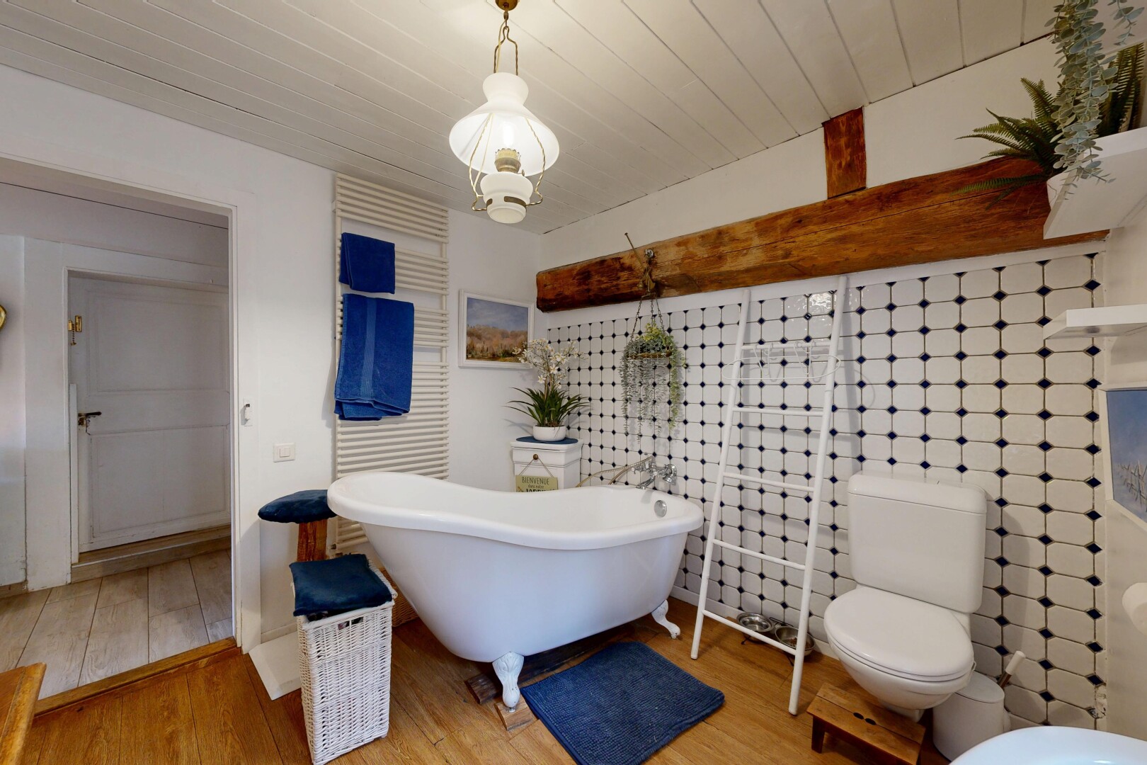 salle de bains avec bain, sol en finition bois, wood finish floor, toilette, et inside property