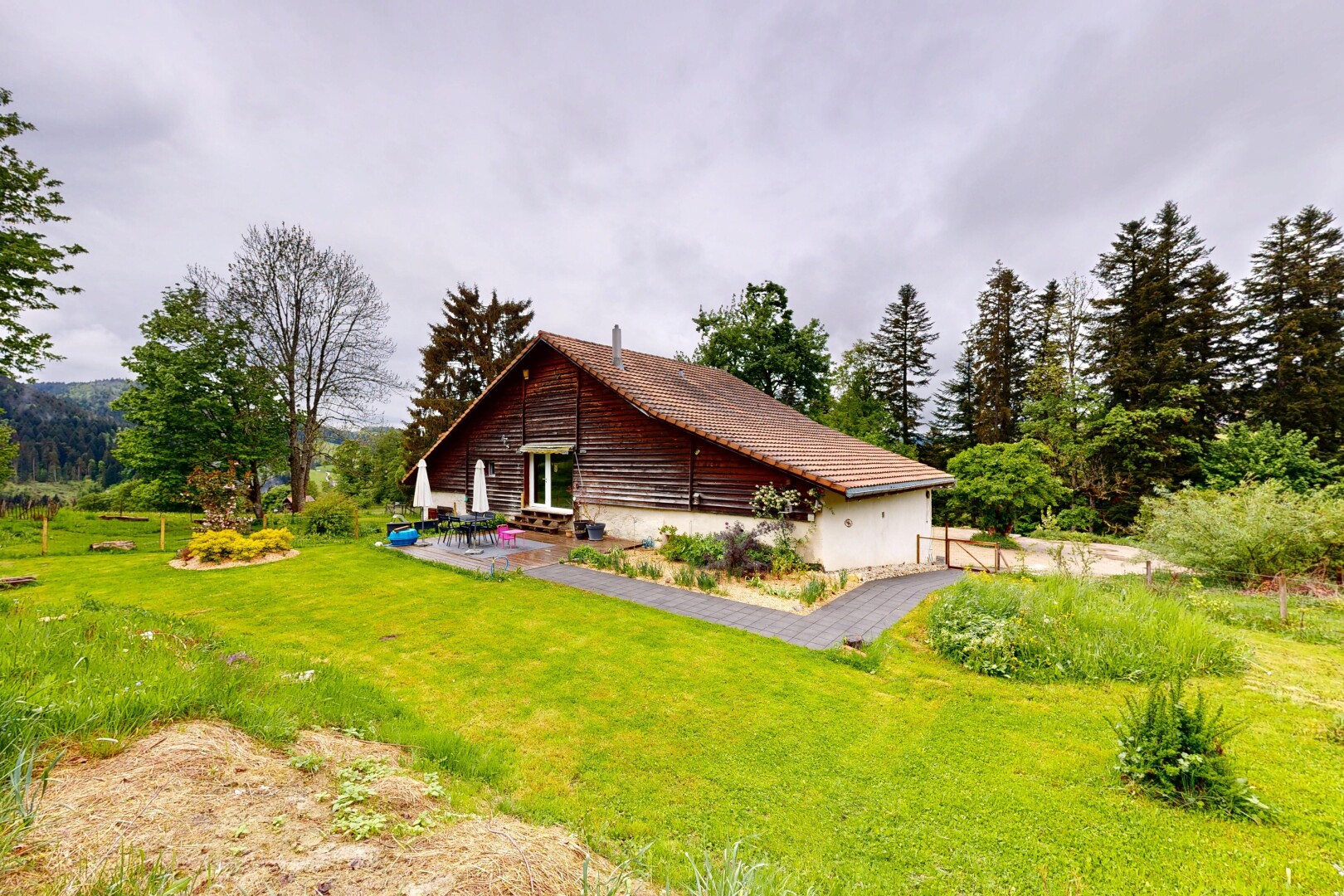 façade avec overcast, pelouse, bardage horizontal, property visible, et woods view