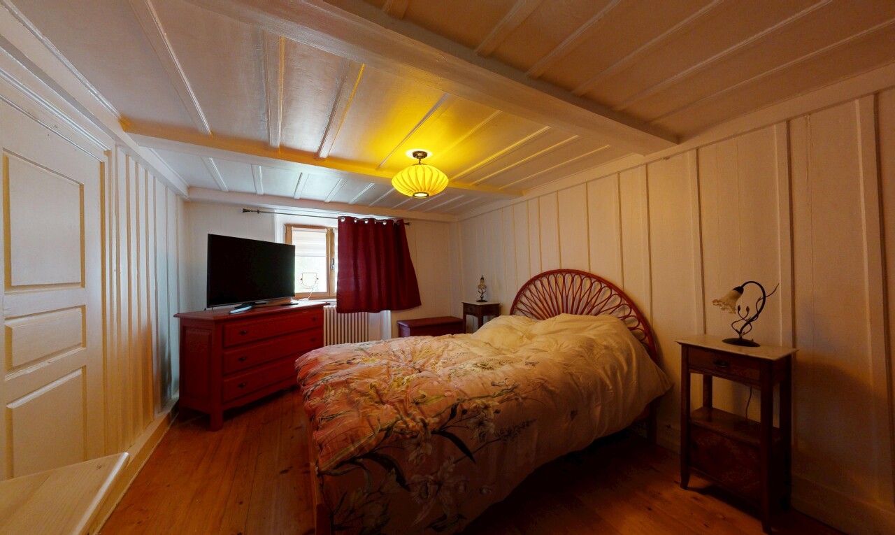 chambre avec wood finish floor, sol en finition bois, inside property, télévision, et paneling wall