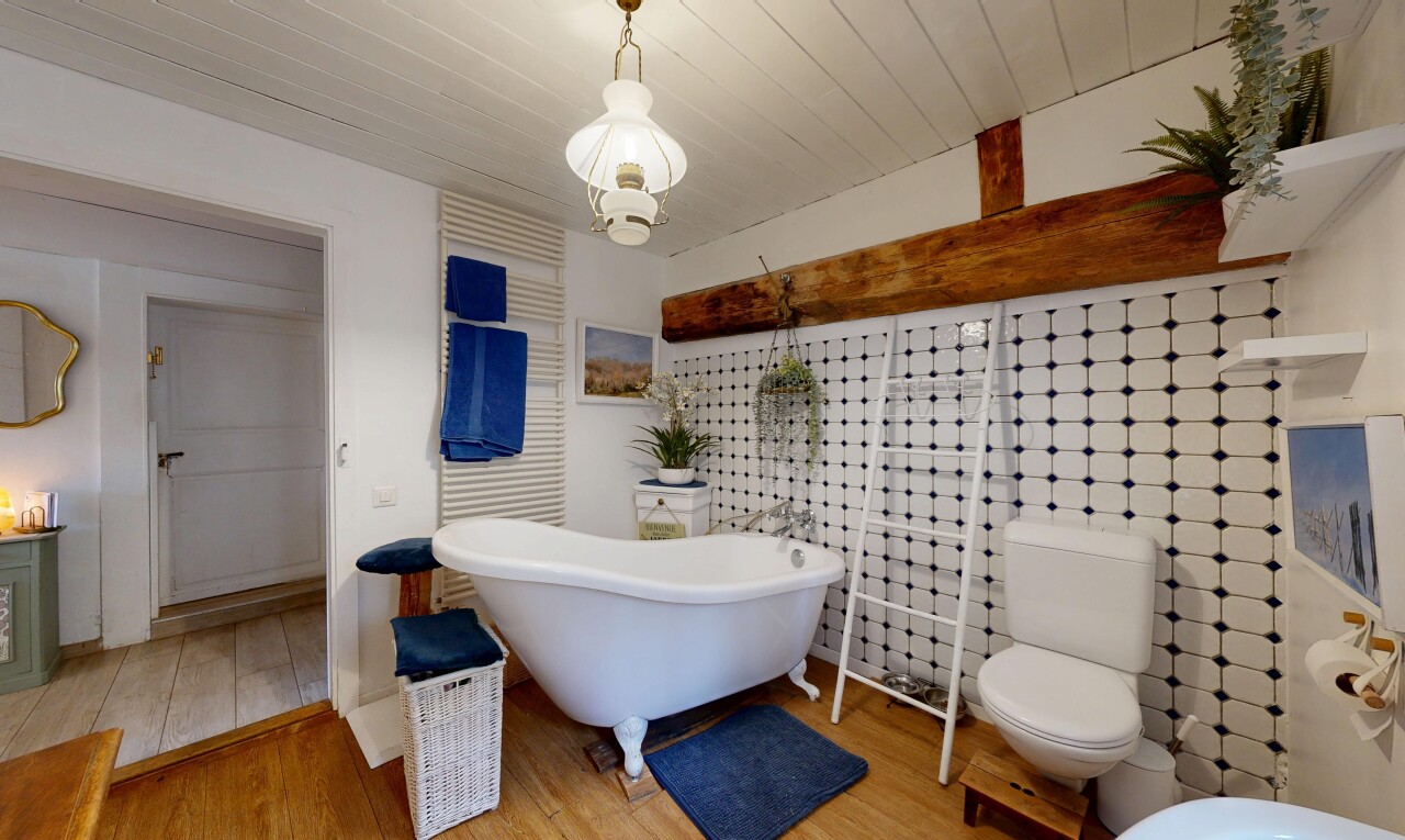 salle de bains avec bain, sol en finition bois, wood finish floor, toilette, et inside property