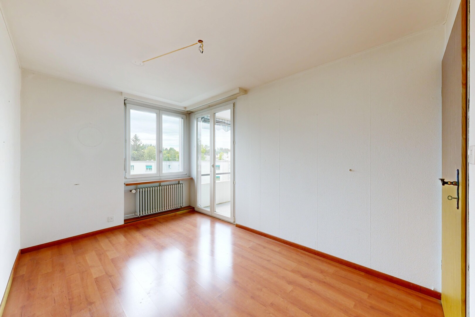 pièce vide avec lumière naturelle, natural light, sol en finition bois, wood finish floor, et radiateur