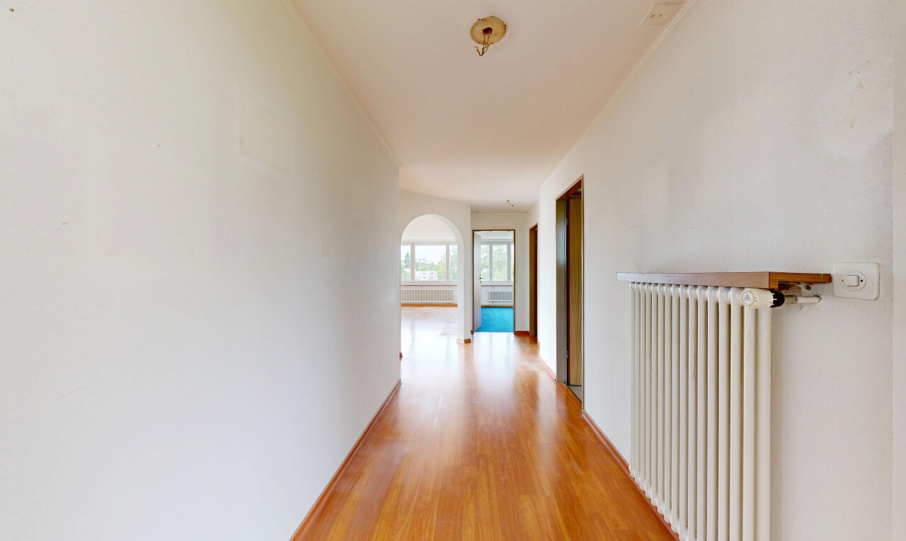 couloir avec cloison sèche, drywall, radiateur, sol en finition bois, et wood finish floor