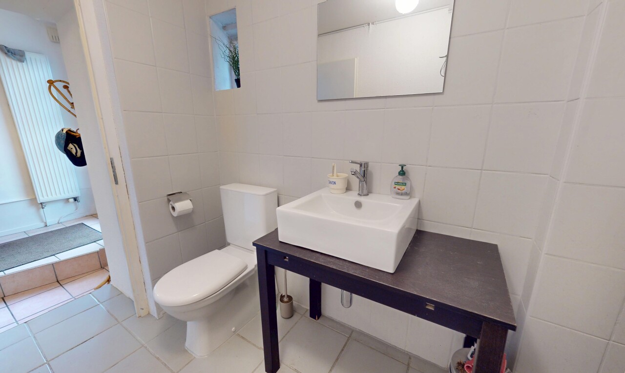 half bath with tile walls, tile patterned floors, vanity, and radiator heating unit