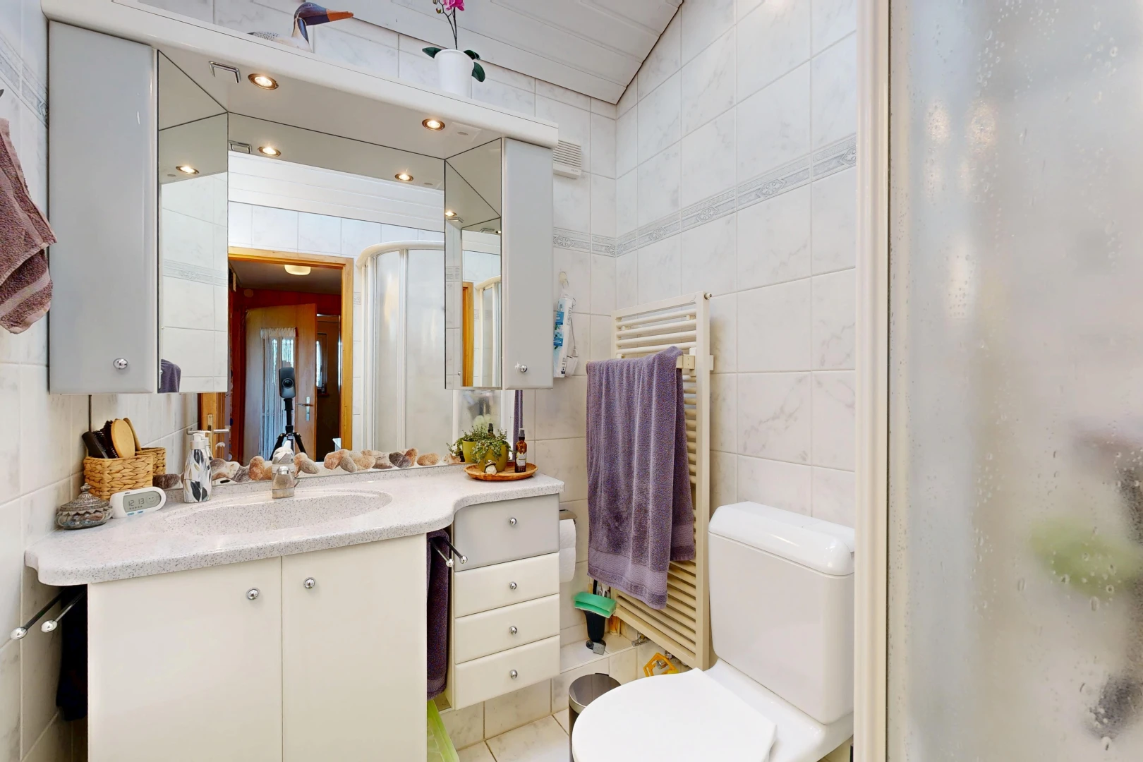 full bathroom with a towel warmer, radiator, tile walls, vanity, and a shower with shower door