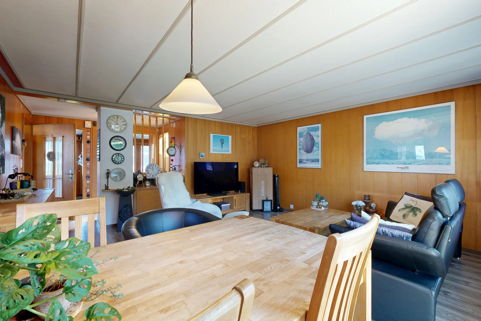 living / dining room with wood walls, decorative light fixtures, and wood finished floors
