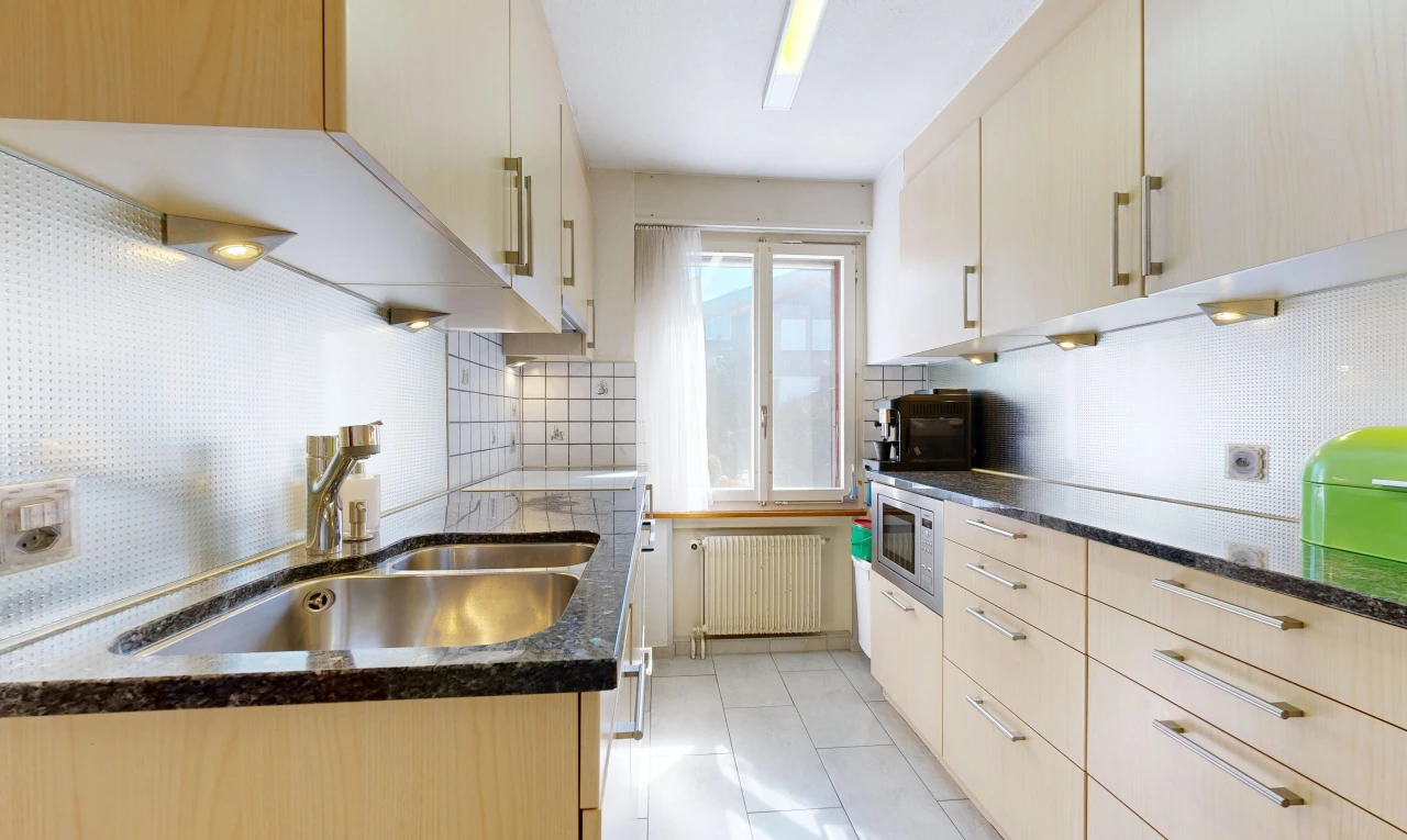 kitchen featuring radiator, decorative backsplash, dark stone counters, and stainless steel microwave