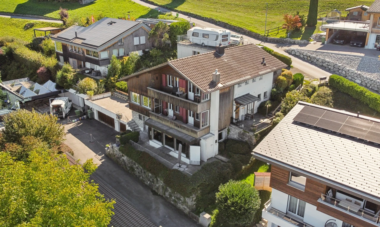 view of property with a balcony, a garage, and driveway