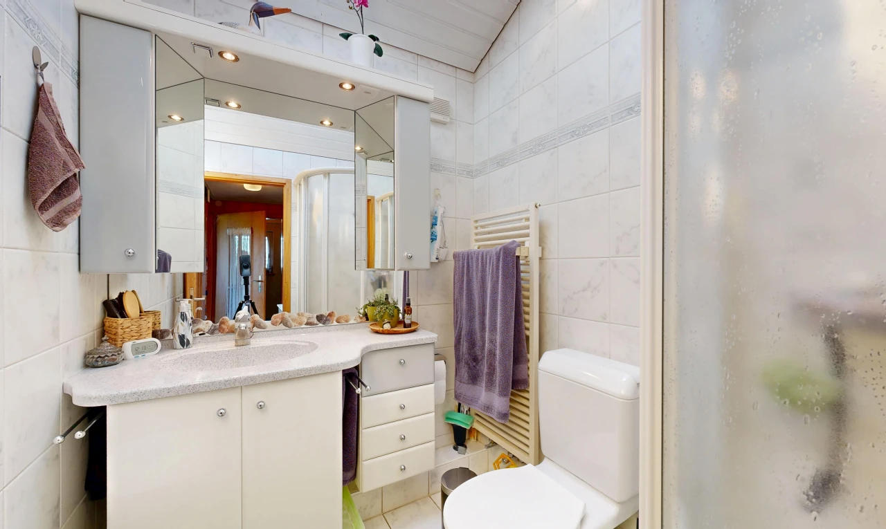 full bathroom with a towel warmer, radiator, tile walls, vanity, and a shower with shower door