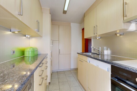 cuisine avec four, plans de travail en pierre, stone countertops, light floor, et dark countertops