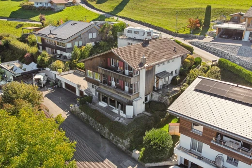 view of property with a balcony, a garage, and driveway