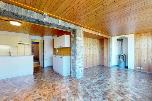 empty room with a wood stove, brick flooring, wooden walls, and wooden ceiling