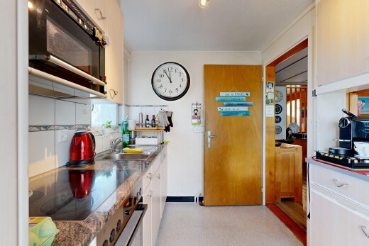 cuisine avec micro-ondes, light floor, plaque de cuisson, évier, et drywall