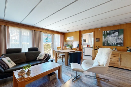 living / dining room with wooden walls, access to exterior, wood finished floors, and hanging light fixtures