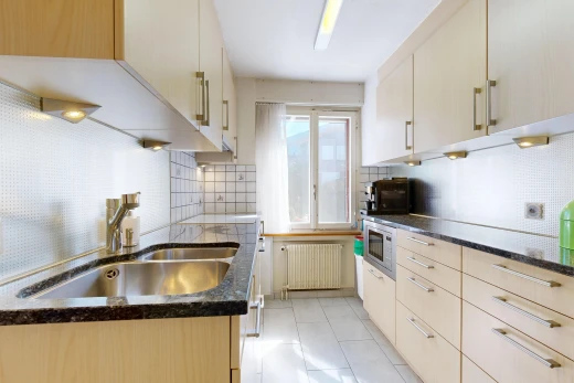 kitchen featuring radiator, decorative backsplash, dark stone counters, and stainless steel microwave
