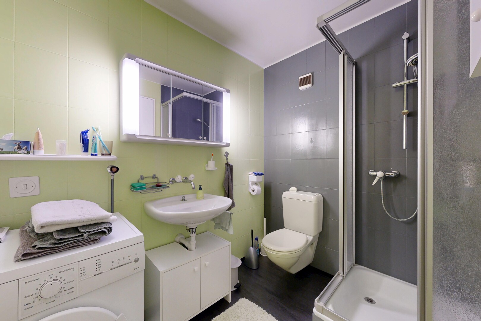 salle de bains avec lave-linge et sèche-linge, miroir, salle de bain complète, douche, et mur en carrelage