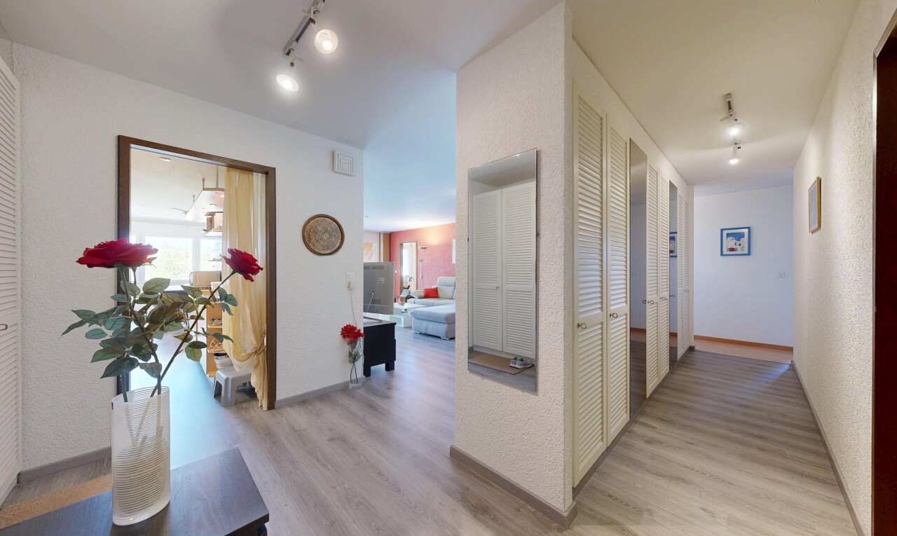 couloir avec inside property, sol en finition bois, wood finish floor, éclairage sur rail, et track lighting