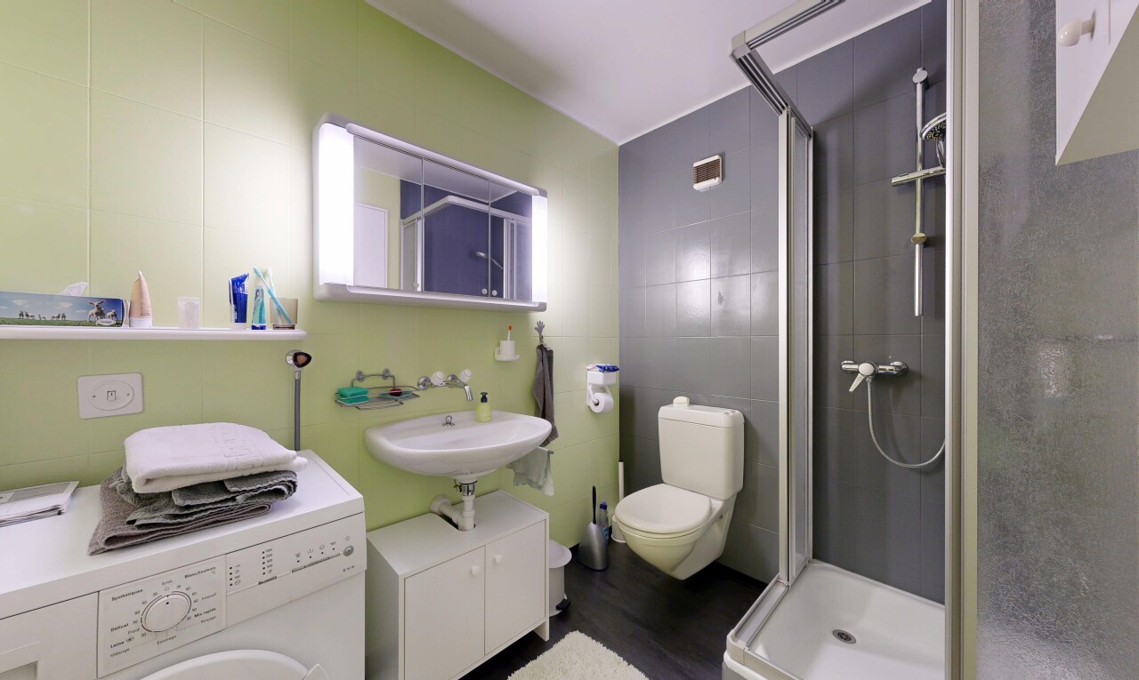 salle de bains avec lave-linge et sèche-linge, miroir, salle de bain complète, douche, et mur en carrelage