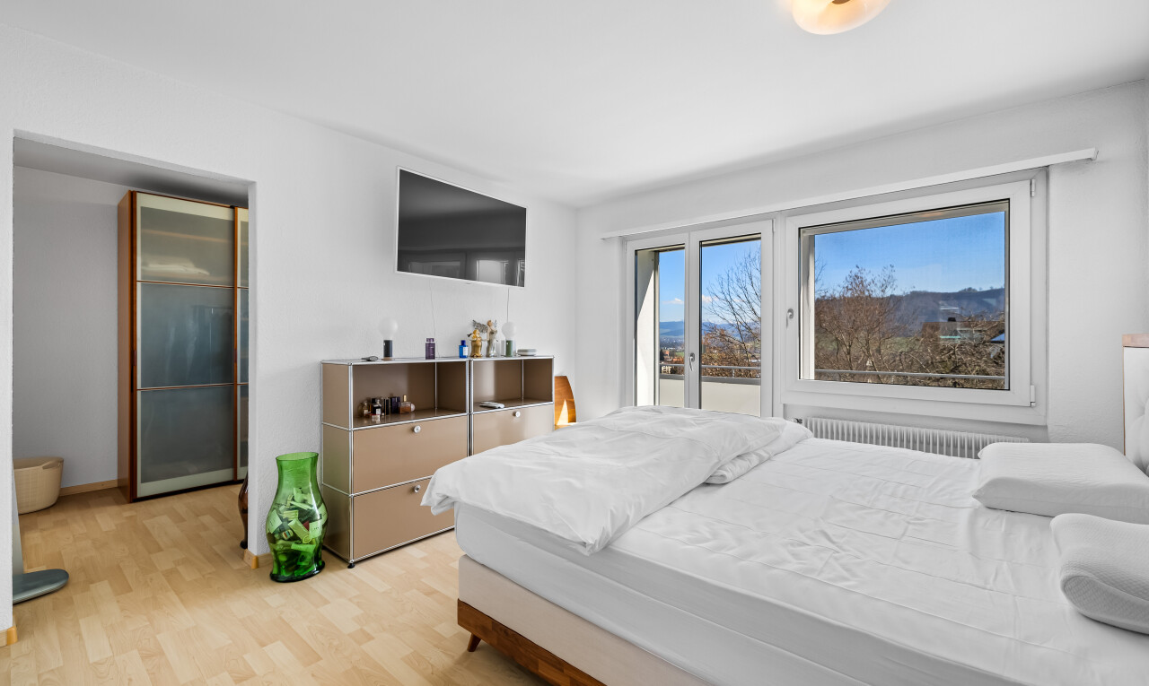 zimmer / schlafzimmer mit fernseher, kühler, natürliches licht, holzfußboden, und gipskartonwand