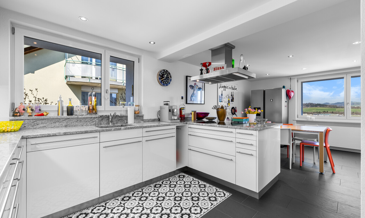 küche mit dunstabzugshaube, küchentheke, kühlschrank, weiße schränke, und natürliches licht