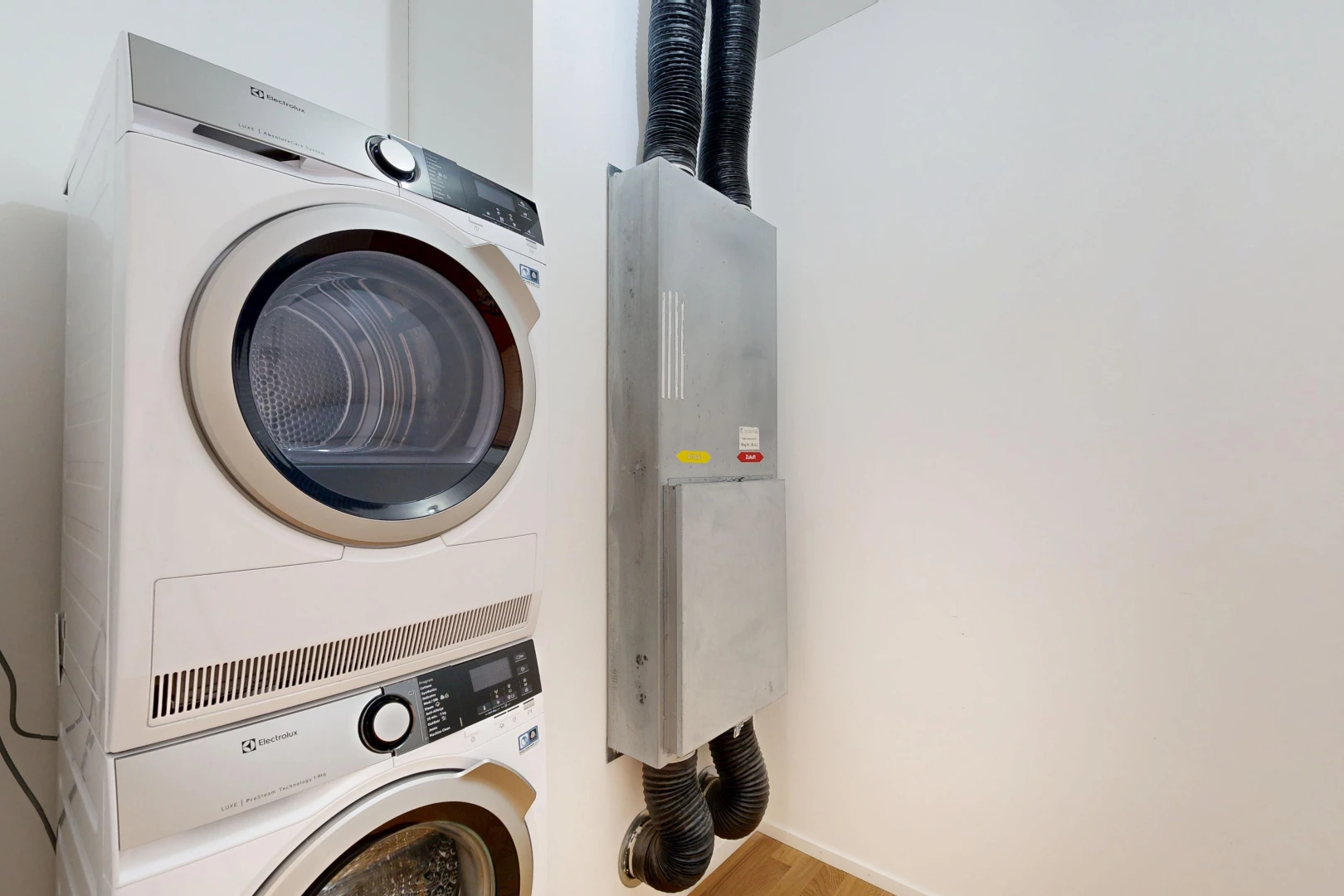 buanderie avec cloison sèche, drywall, lave-linge et sèche-linge superposés, sol en finition bois, et wood finish floor