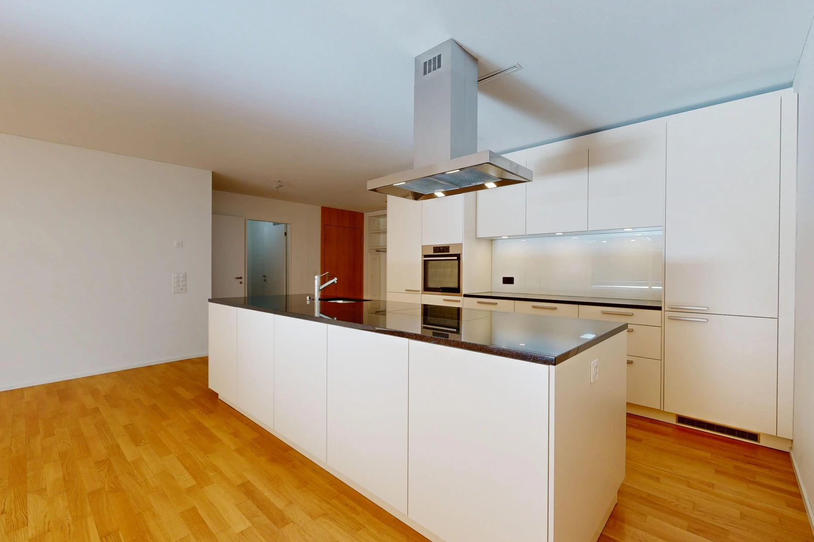 cuisine avec hotte, dark countertops, plans de travail, light floor, et flat panel cabinets