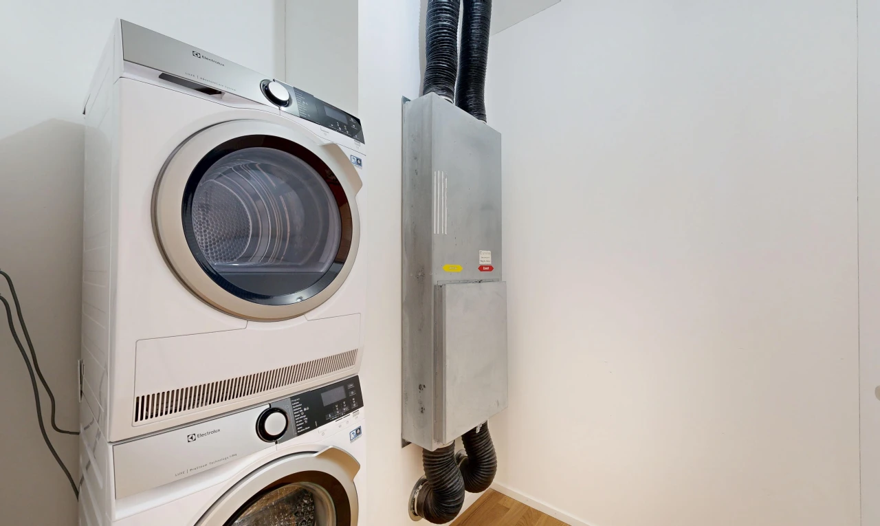 buanderie avec cloison sèche, drywall, lave-linge et sèche-linge superposés, sol en finition bois, et wood finish floor