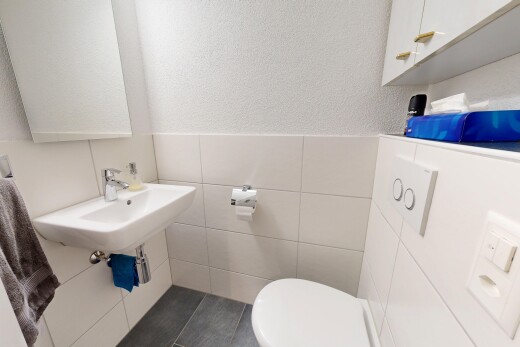 bathroom with tile walls, dark tile patterned flooring, a wainscoted wall, and a textured wall