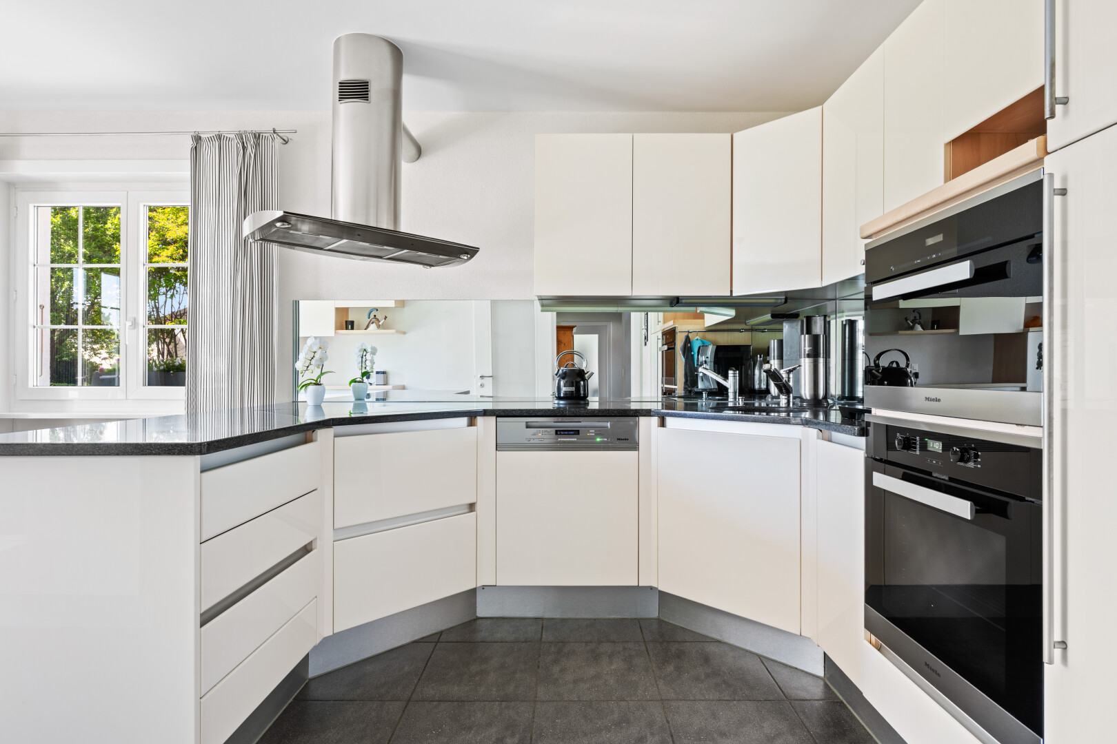 kitchen featuring exhaust hood, white cabinets, white dishwasher, and multiple ovens