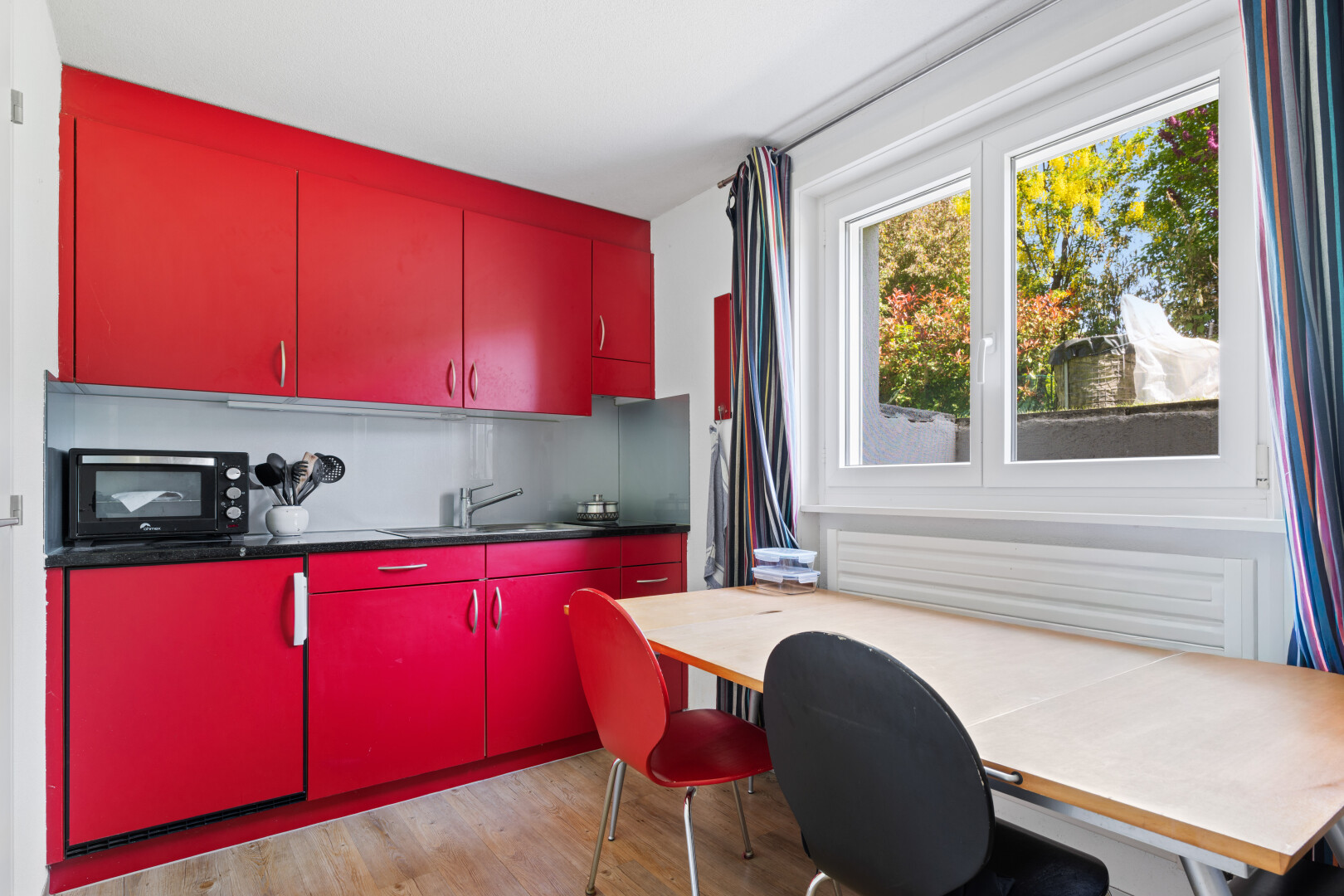 kitchen with red cabinetry, light wood finished floors, black microwave, and an office area