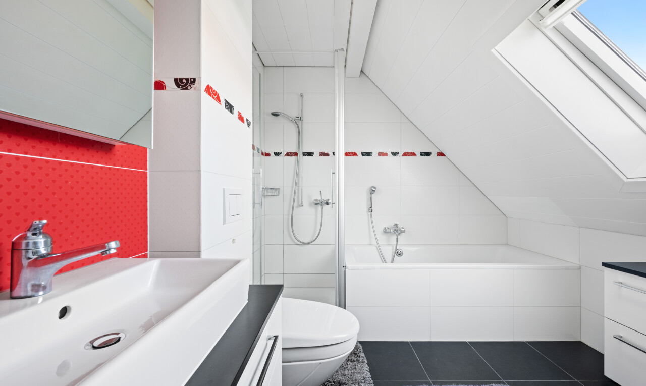 full bath featuring vanity, vaulted ceiling, tiled shower / bath combo, dark tile patterned flooring, and a skylight