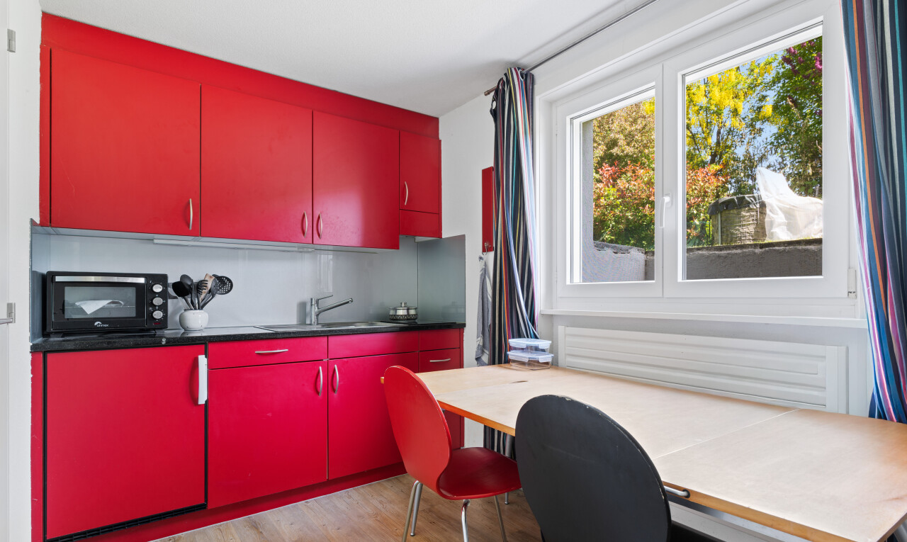 cuisine avec red cabinets, armoires rouges, dark countertops, inside property, et wood finish floor