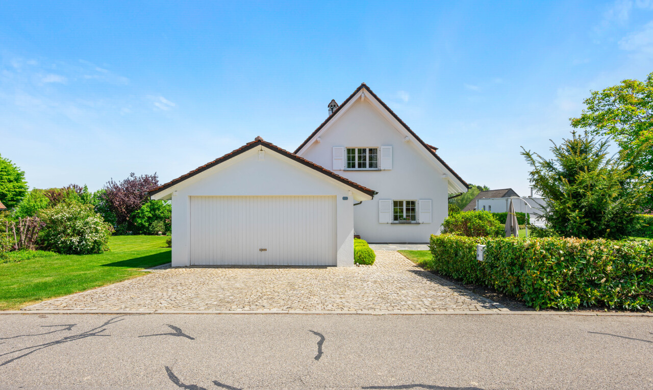 façade avec property visible, allée, day time, bardage en stuc, et garage attaché