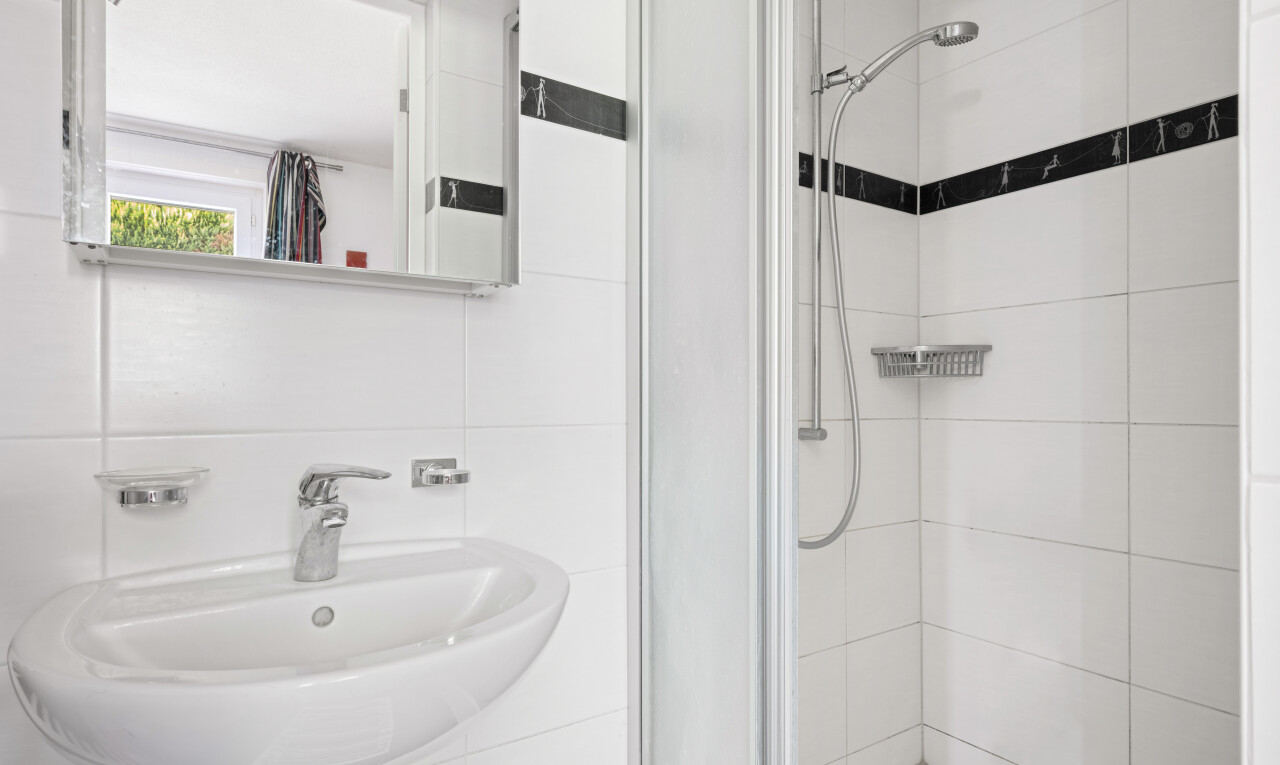 salle de bains avec miroir, douche, évier, salle de bain complète, et inside property