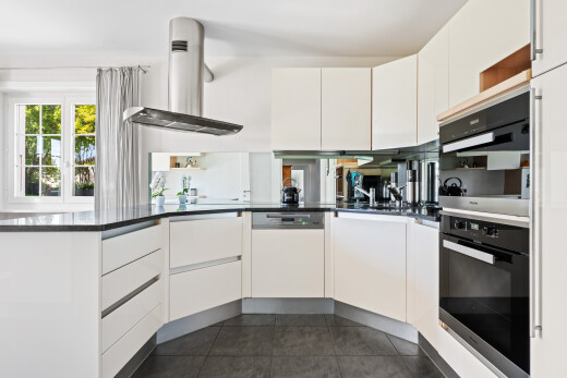 kitchen featuring exhaust hood, white cabinets, white dishwasher, and multiple ovens