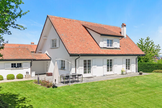 outdoor house featuring a chimney, a patio area, stucco siding, and a lawn